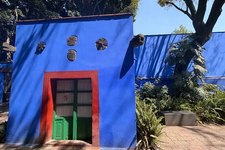Front view of La Casa Azul showing the cobalt blue facade with red door and plaster details — 20th century Mexican colonial style